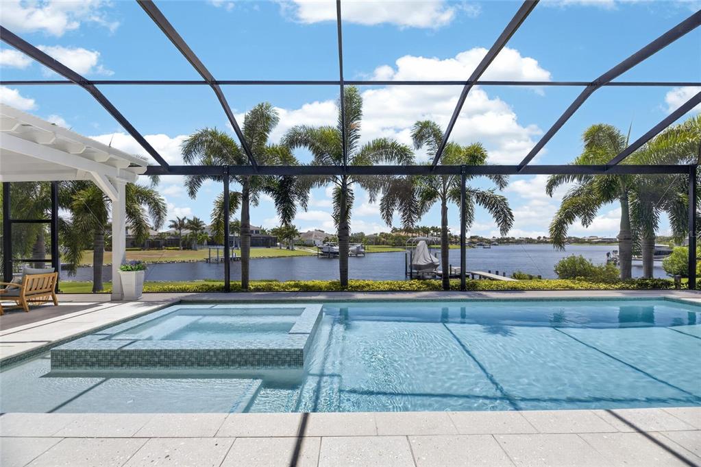 A swimming pool and spa sit inside a screened lanai overlooking a waterfront canal — 825 MANNS HARBOR DRIVE, APOLLO BEACH, FL
