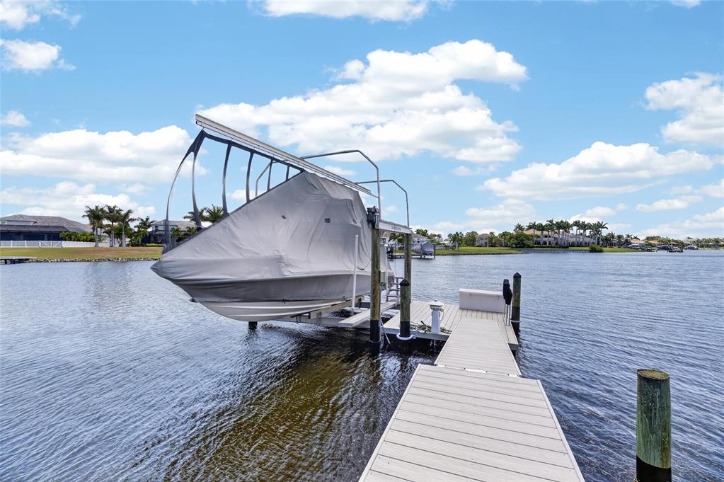 A boat covered by a canopy sits on a mechanical lift at the end of a dock — 825 MANNS HARBOR DRIVE, APOLLO BEACH, FL