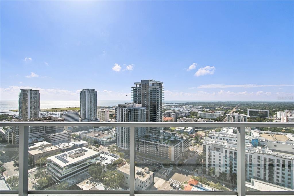 A high-rise balcony features outdoor seating, potted plants, and a dining table overlooking a city — 400 CENTRAL AVENUE UNIT 2505, ST PETERSBURG, FL