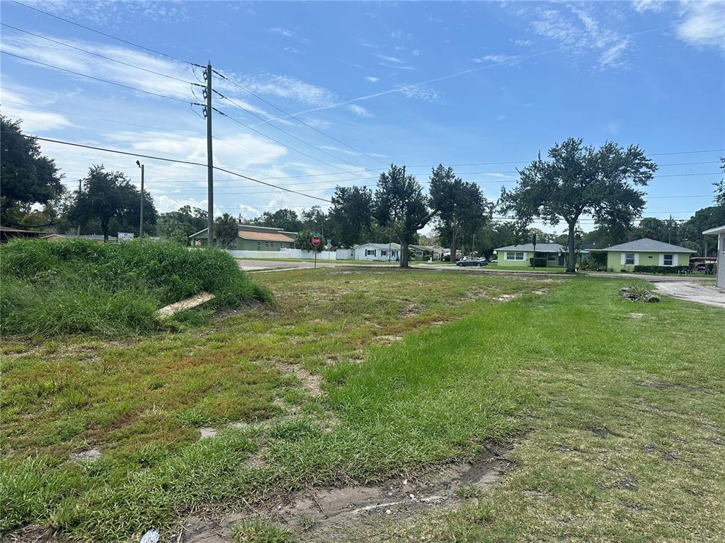 A vacant, grassy residential lot with scattered trees and utility poles under a blue sky — 801 22ND AVENUE S, ST PETERSBURG, FL