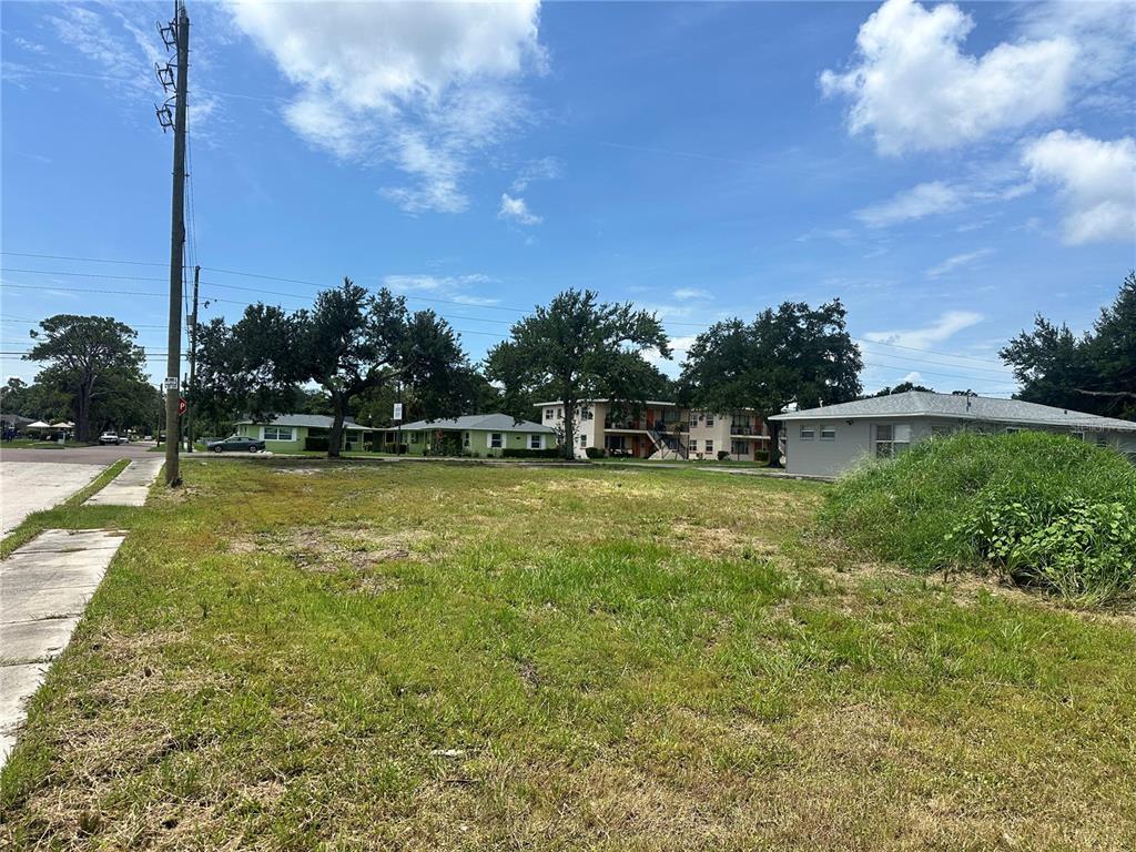 A vacant grassy lot sits in front of several apartment buildings under a blue sky — 801 22ND AVENUE S, ST PETERSBURG, FL