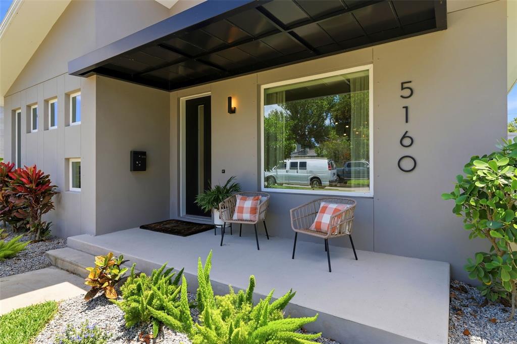 An open-concept kitchen and dining area features dark cabinetry, a black island, and wood flooring — 5160 DARTMOUTH AVENUE N, ST PETERSBURG, FL