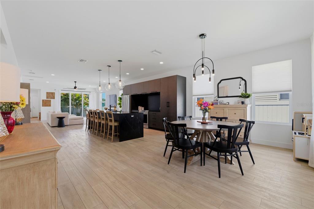 A dining room features a round wooden table, black chairs, and a modern light fixture — 5160 DARTMOUTH AVENUE N, ST PETERSBURG, FL