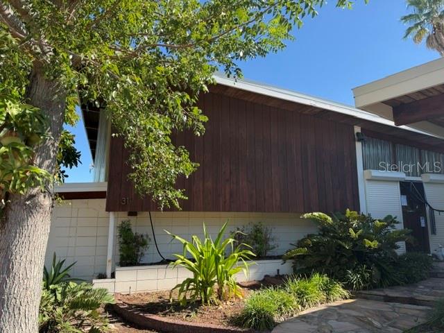 An exterior entryway features a stone path, a wooden door with shutters, and tropical landscaping — 31 DOLPHIN DRIVE, TREASURE ISLAND, FL