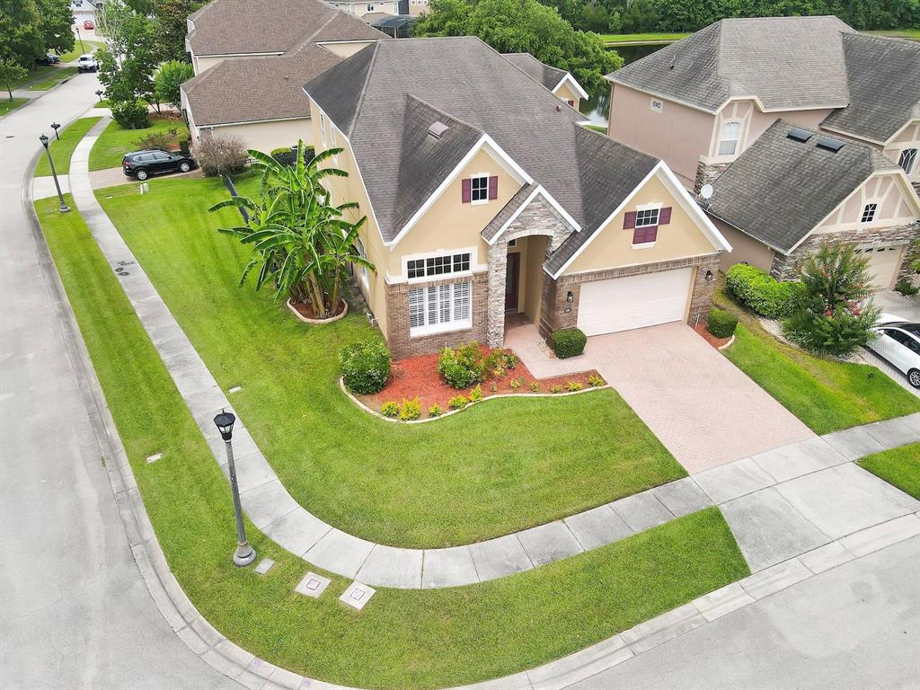 An aerial view shows a tan, single-family home with a stone facade and paved driveway — 930 SPRING OAK CIRCLE, ORLANDO, FL