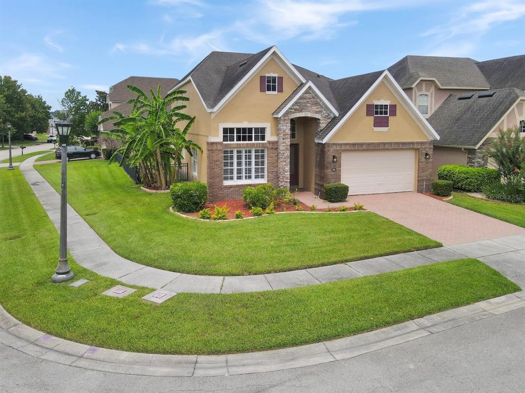 A tan suburban house with a stone facade, a two-car garage, and a manicured lawn — 930 SPRING OAK CIRCLE, ORLANDO, FL