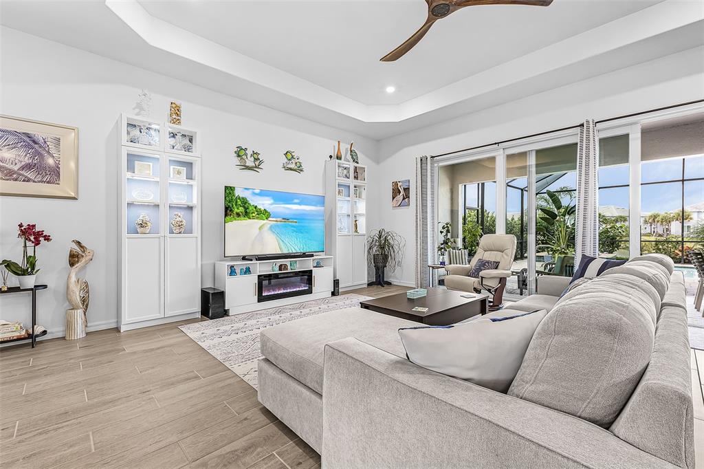 A living room features a tray ceiling, light wood-look tile floors, and a large sectional — 14856 REDBUD LANE, PUNTA GORDA, FL