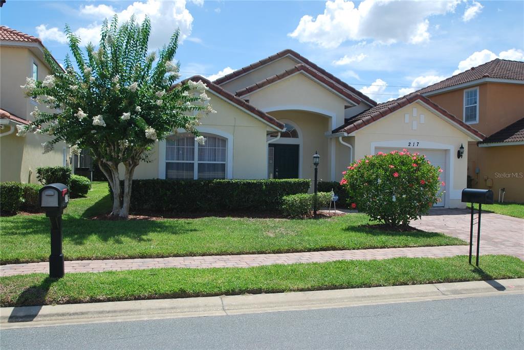 A single-story suburban house with a tan stucco exterior, a tiled roof, and a front lawn — 217 ROBIN ROAD, DAVENPORT, FL