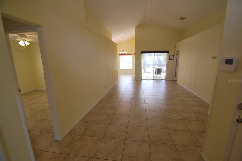An interior view shows a tiled living area with vaulted ceilings and sliding glass doors — 217 ROBIN ROAD, DAVENPORT, FL