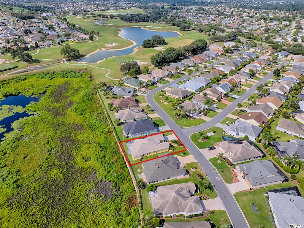An aerial view shows a single-story house with a red outline bordering a large wetland — 622 MAYBANK LOOP, THE VILLAGES, FL