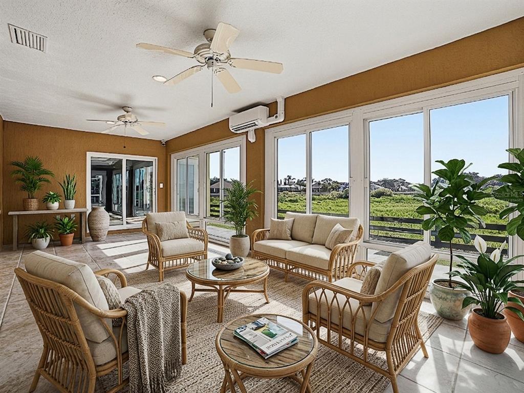 A sunroom with wicker furniture, ceiling fans, and large windows overlooking a grassy field — 622 MAYBANK LOOP, THE VILLAGES, FL