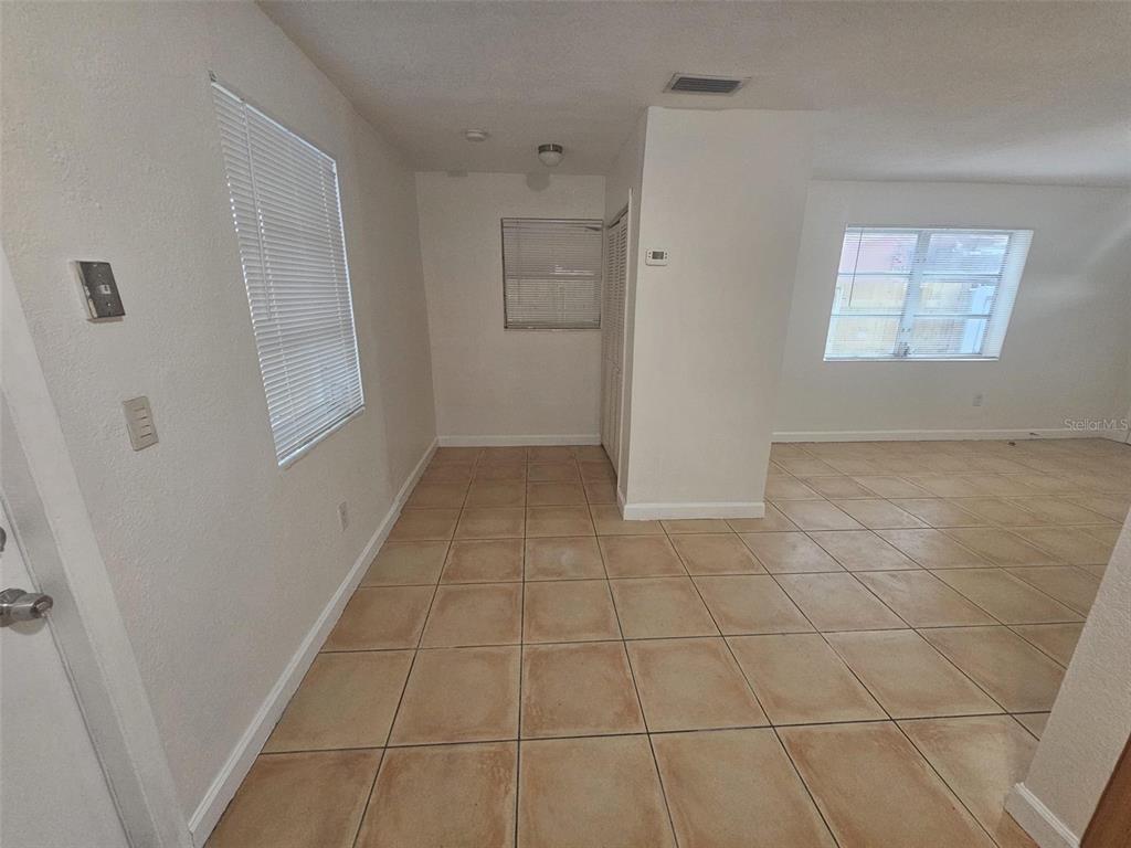 An interior view shows a room with beige tile flooring, white walls, and two windows — 4785 NW 2ND STREET, MIAMI, FL