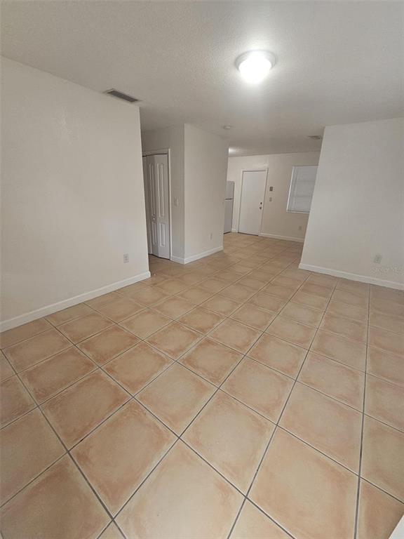 An interior view of a room with beige tile flooring, white walls, and a ceiling light — 4785 NW 2ND STREET, MIAMI, FL