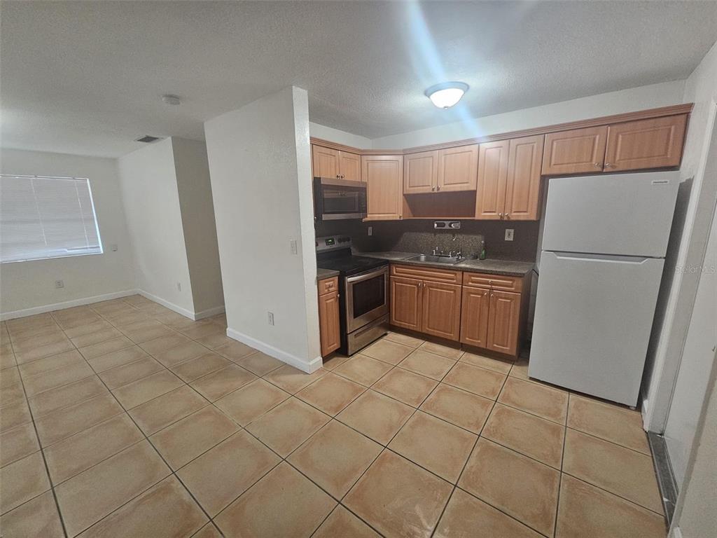 A kitchen with light wood cabinets, stainless steel appliances, and tan tile flooring — 4785 NW 2ND STREET, MIAMI, FL