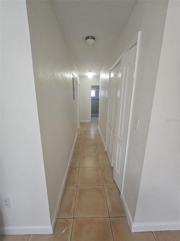 A narrow hallway features light-colored tile flooring, white walls, and a white bi-fold closet door — 4785 NW 2ND STREET, MIAMI, FL