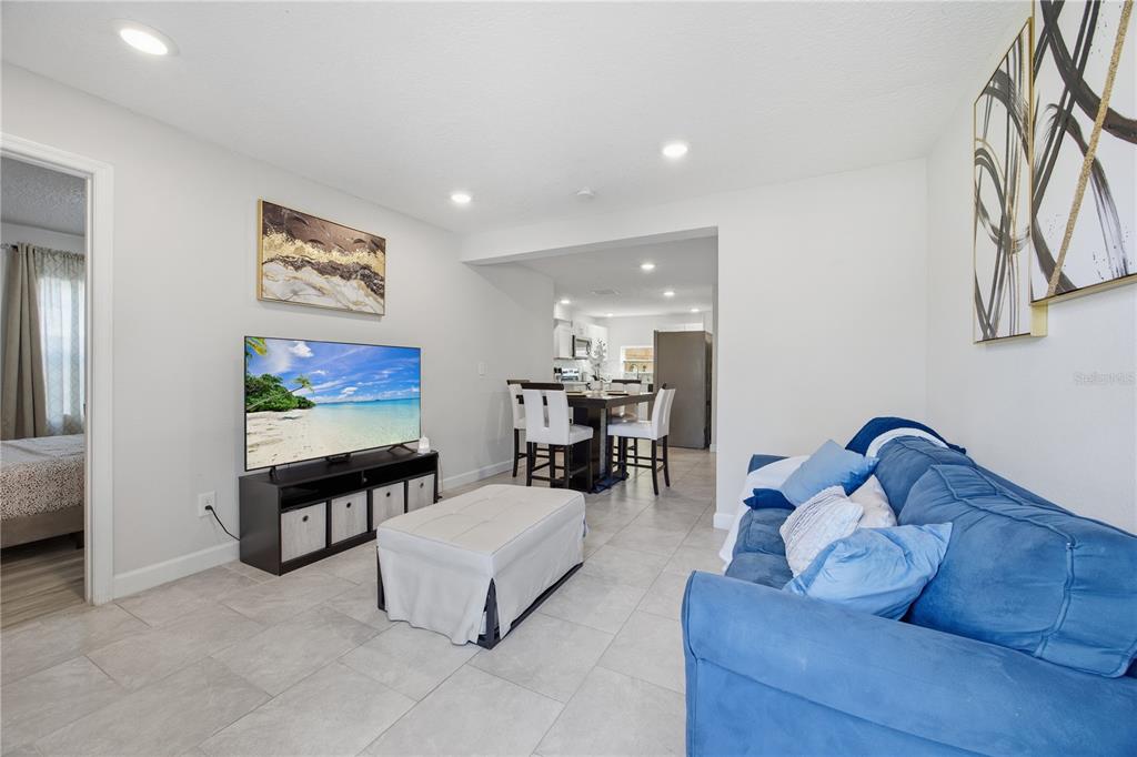 A living room with a blue sofa, a television on a stand, and a dining area — 2350 VALLEY DRIVE, APOPKA, FL