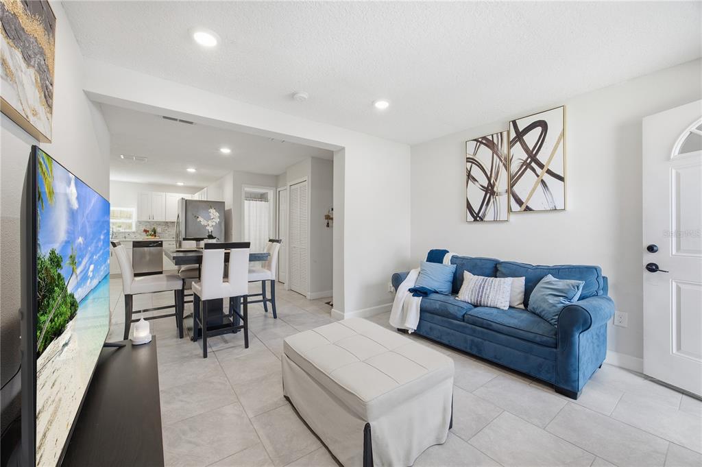 A living room with a blue sofa and ottoman opens into a kitchen with dining area — 2350 VALLEY DRIVE, APOPKA, FL