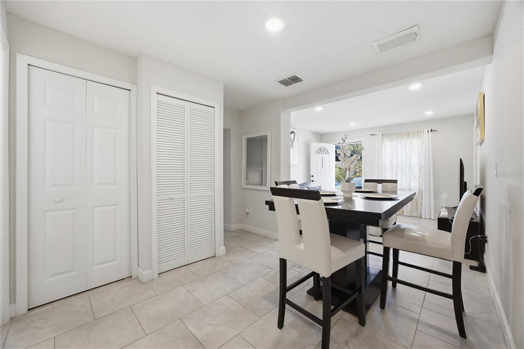 A dining area with a dark table, white chairs, tiled floors, and two closet doors — 2350 VALLEY DRIVE, APOPKA, FL