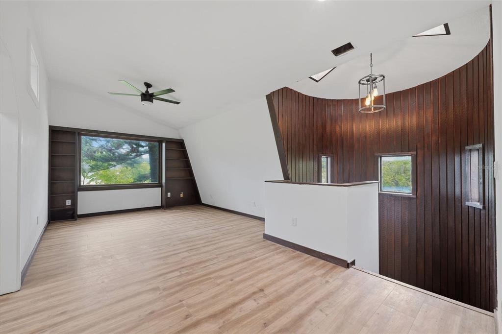 An upstairs loft area features wood-paneled curved walls, a large window, and light wood flooring — 15017 DAYTON DRIVE, HUDSON, FL