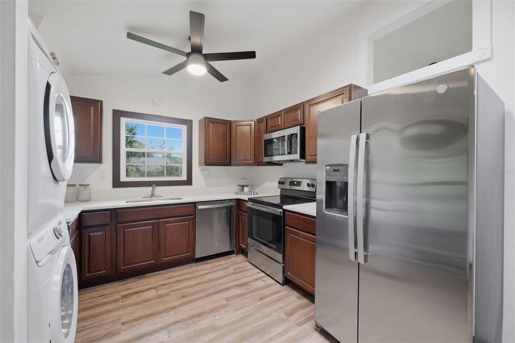 A kitchen with dark wood cabinets, stainless steel appliances, and a stacked washer and dryer — 15017 DAYTON DRIVE, HUDSON, FL