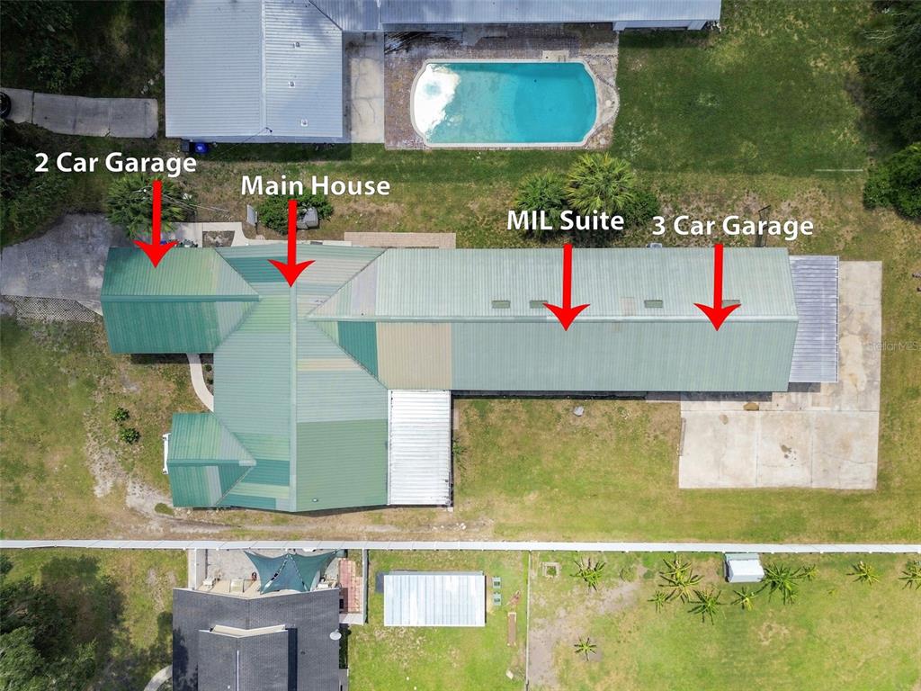 An aerial view shows a house with a metal roof, a pool, and multiple garages — 2219 NEW JERSEY RD, LAKELAND, FL