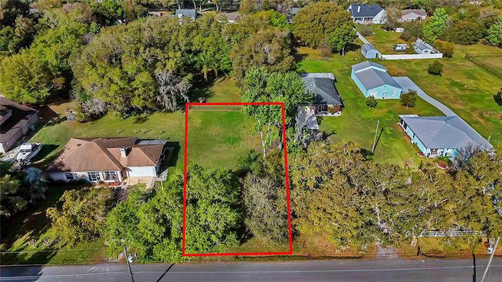 An aerial view shows a rectangular vacant lot outlined in red between two residential houses — 0 GRAPE AVENUE, ST CLOUD, FL