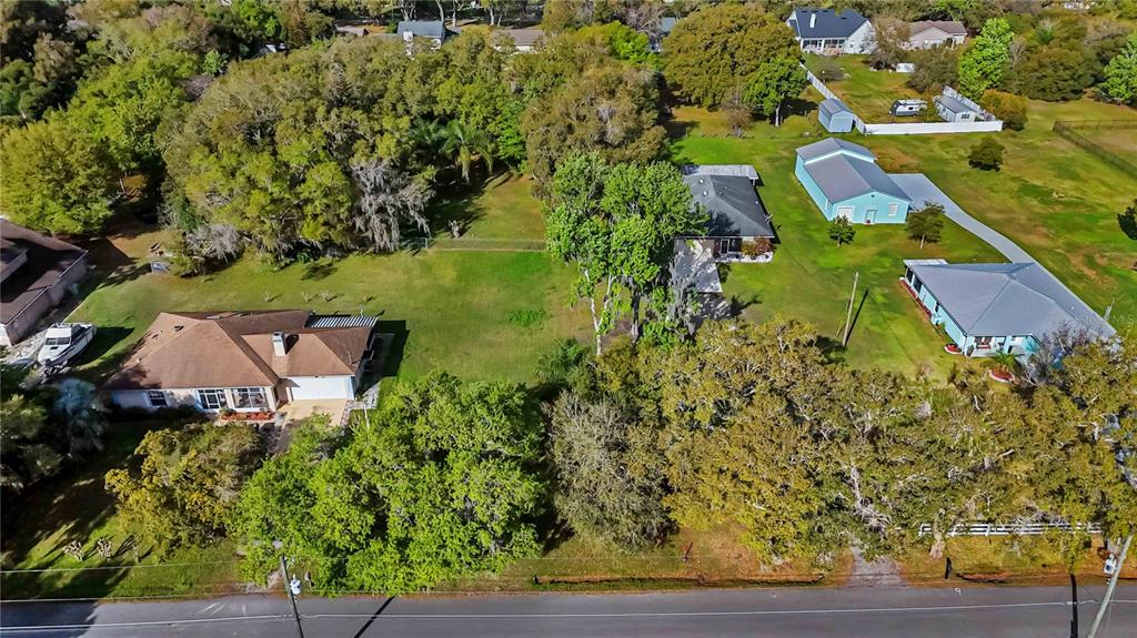 An aerial view shows two houses on large, tree-filled lots next to a paved road — 0 GRAPE AVENUE, ST CLOUD, FL