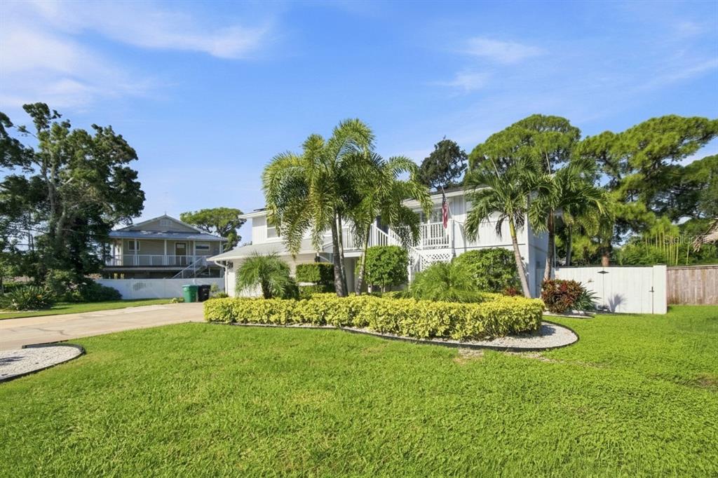 A two-story house with a white exterior, palm trees, and a landscaped hedge in front — 201 LAGOON DRIVE, PALM HARBOR, FL