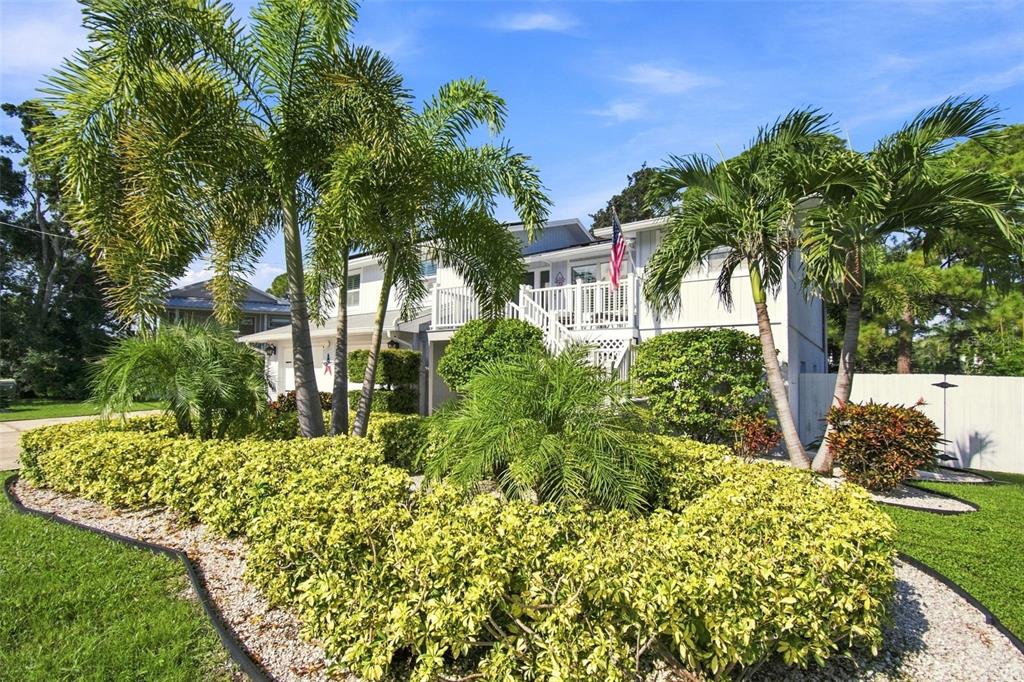 A two-story white house with a front staircase, palm trees, and manicured hedges — 201 LAGOON DRIVE, PALM HARBOR, FL