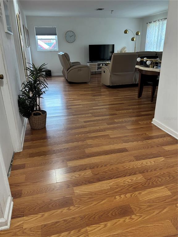 A living room features wood-look flooring, a television, and two tan reclining chairs — 1706 MARGATE BOULEVARD, LEHIGH ACRES, FL