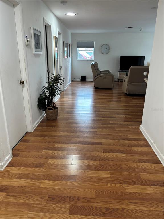 A living room features wood-look flooring, two beige recliners, and a television on a stand — 1706 MARGATE BOULEVARD, LEHIGH ACRES, FL