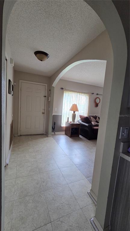 A tiled entryway leads through an arched doorway into a living room with a window — 36 BRADFORD COURT, KISSIMMEE, FL