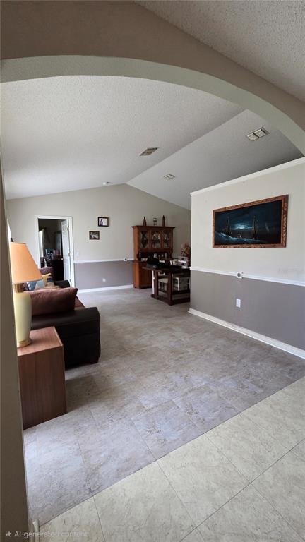 A living room features a vaulted ceiling, tiled floors, and an arched entryway — 36 BRADFORD COURT, KISSIMMEE, FL