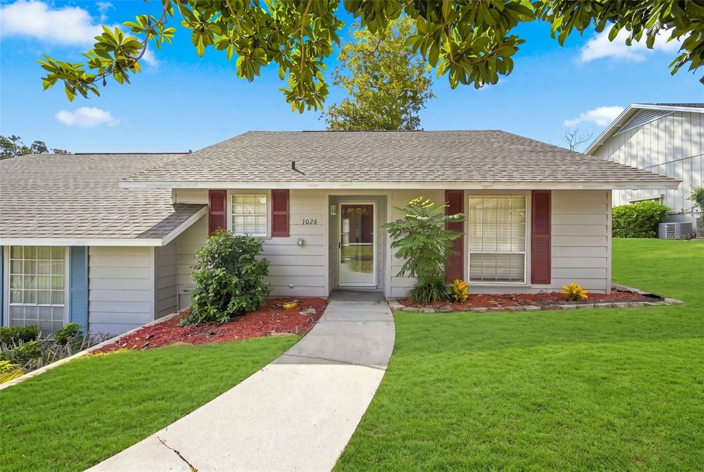 A single-story house with gray siding, red shutters, and a concrete walkway leading to the entrance — 1026 VILLA LANE UNIT 14, APOPKA, FL