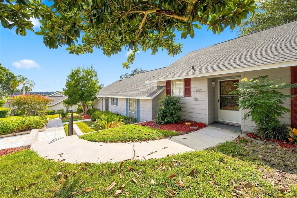 A single-story house with gray siding, a shingled roof, and a paved walkway leading to the entrance — 1026 VILLA LANE UNIT 14, APOPKA, FL