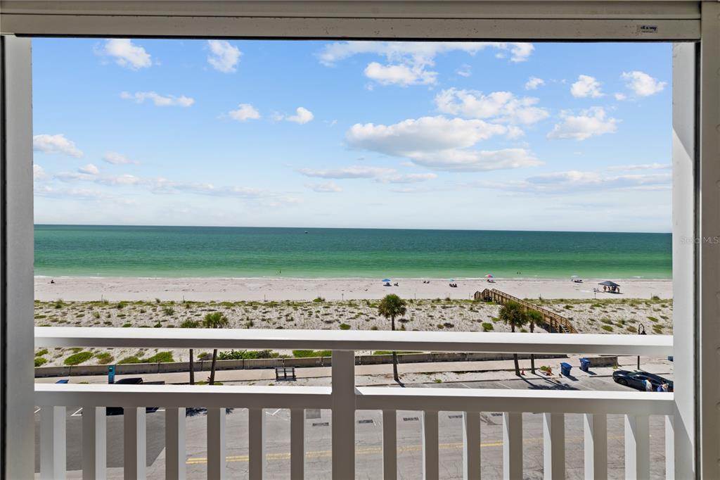 A balcony view overlooking a sandy beach, ocean, and a parking lot below — 555 GULF WAY UNIT 6S, ST PETE BEACH, FL