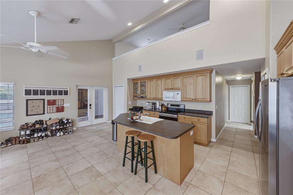 A kitchen with light wood cabinets, a central island, and tile flooring in an open space — 2024 LARKSPUR COURT, TRINITY, FL