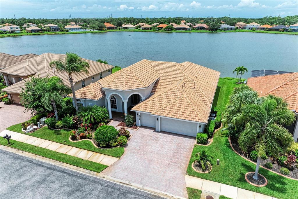 An aerial view of a single-story house with a tile roof and a lakefront backyard — 6988 74TH STREET CIRCLE E, BRADENTON, FL