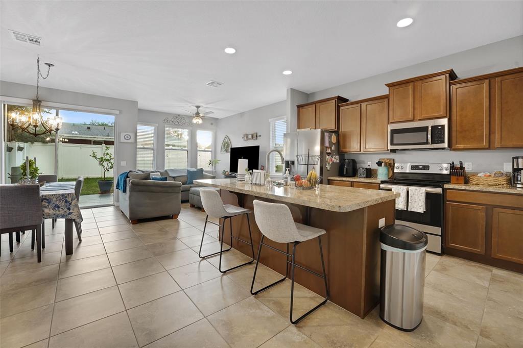 An open-concept kitchen and living area features wood cabinets, granite countertops, and tile flooring — 1664 PETERSON PLACE, SANFORD, FL