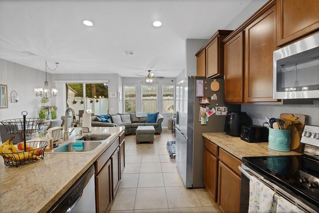 A kitchen with wood cabinets and granite countertops overlooks an open-concept living and dining area — 1664 PETERSON PLACE, SANFORD, FL