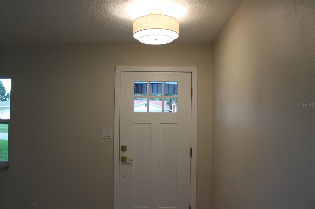 An interior view of an entryway featuring a white door with glass panels and lighting — 7015 CRESTLAKE DRIVE, ORLANDO, FL