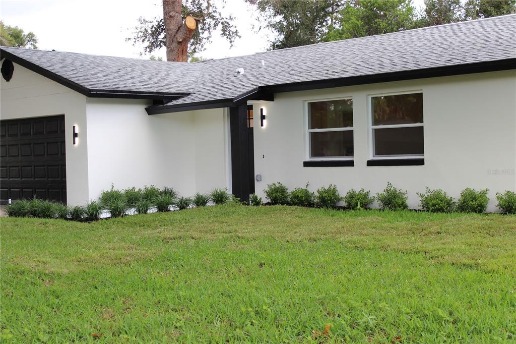 A white single-story house with a black garage door, black trim, and a manicured lawn — 7015 CRESTLAKE DRIVE, ORLANDO, FL