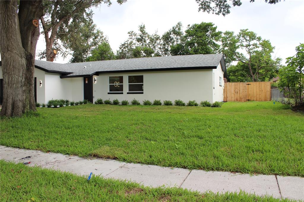 A single-story white house with a dark roof and black trim sits behind a lawn — 7015 CRESTLAKE DRIVE, ORLANDO, FL
