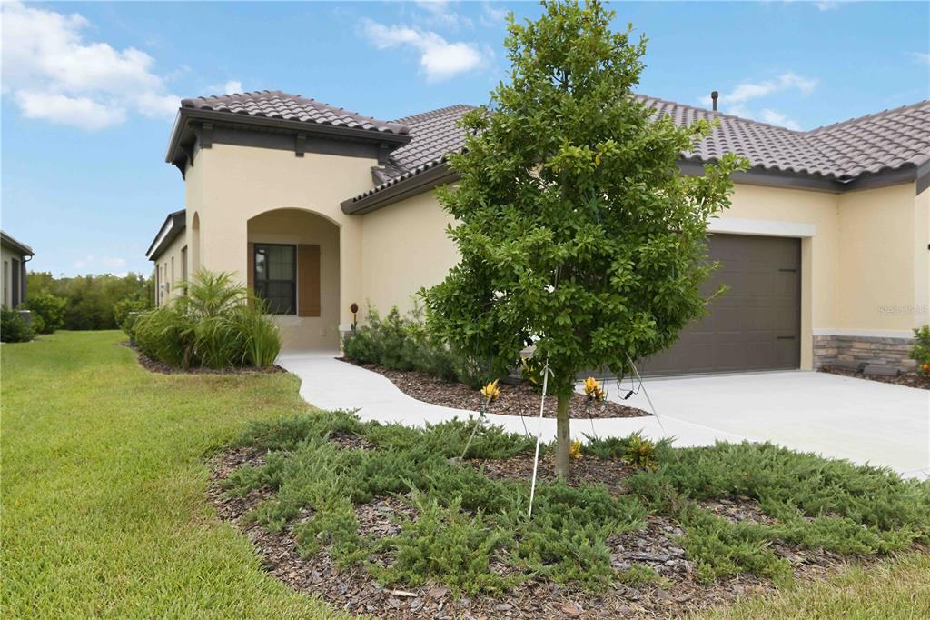 A single-story house with a beige stucco exterior, a tiled roof, and a concrete driveway — 244 ALTAMURA CIRCLE, NOKOMIS, FL