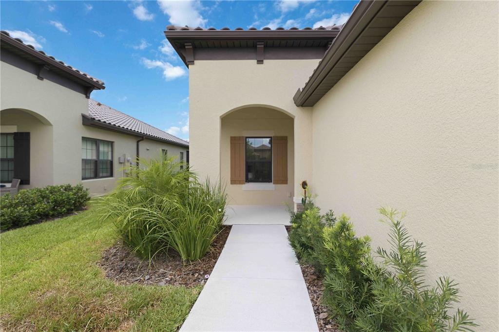 A concrete walkway leads to the recessed front entrance of a beige stucco house — 244 ALTAMURA CIRCLE, NOKOMIS, FL