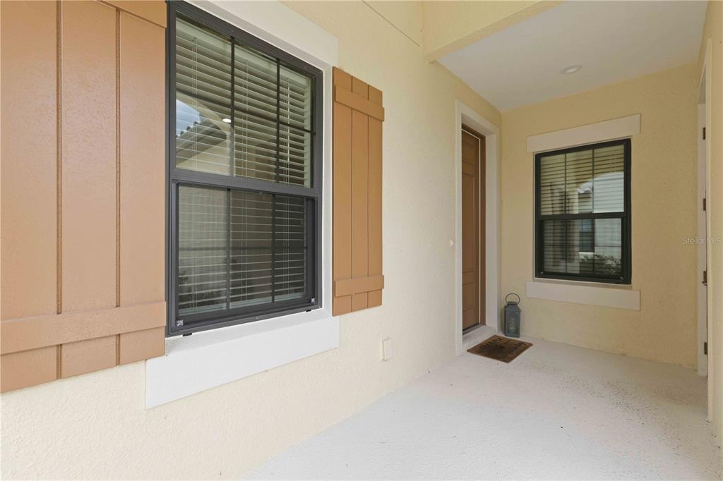 A covered entryway features a front door, two windows with shutters, and a concrete floor — 244 ALTAMURA CIRCLE, NOKOMIS, FL