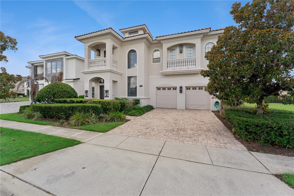 A two-story beige house with a paver driveway, two-car garage, and second-floor balconies — 304 MUIRFIELD LOOP, REUNION, FL