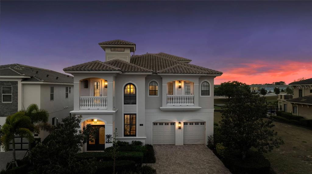 A two-story house with a tiled roof, two balconies, and a two-car garage at sunset — 304 MUIRFIELD LOOP, REUNION, FL