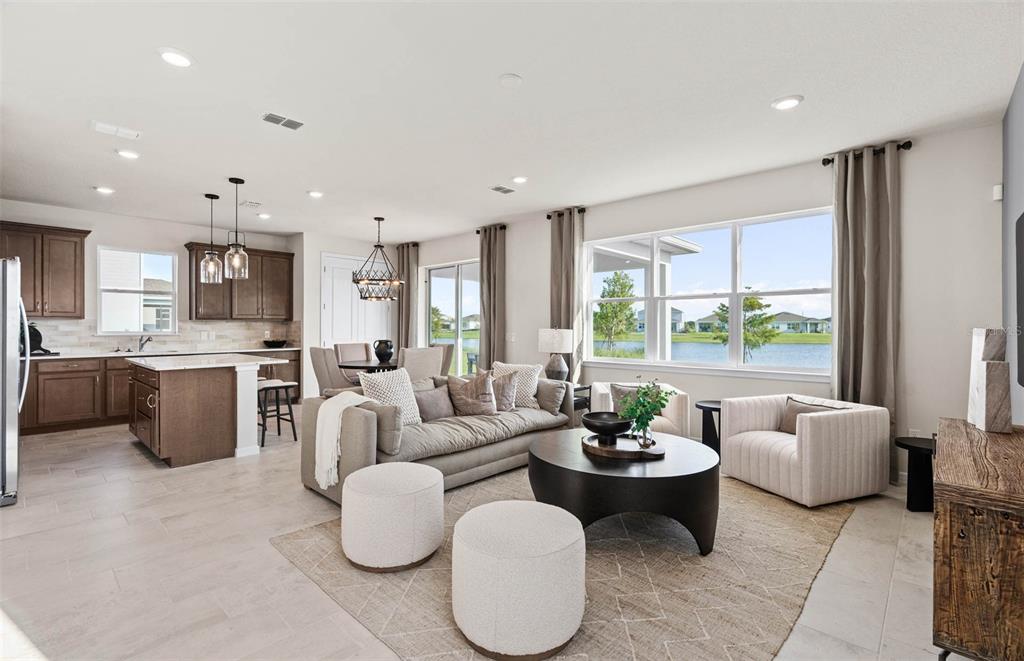 An open-concept living room and kitchen featuring a large island, neutral furniture, and lake views — 5514 FREESIA DRIVE, LAKELAND, FL