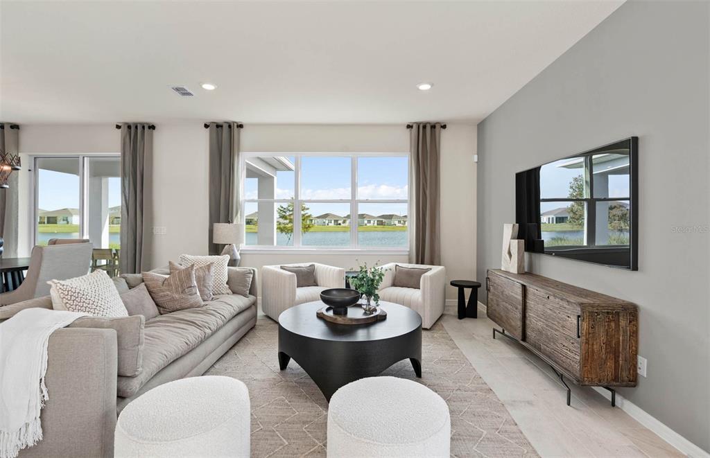 A living room features a gray sofa, two armchairs, a round coffee table, and a television — 5514 FREESIA DRIVE, LAKELAND, FL